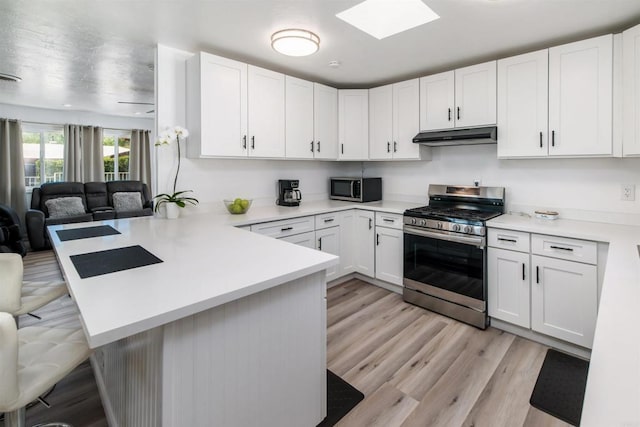 kitchen with stainless steel appliances, light countertops, a peninsula, and white cabinetry