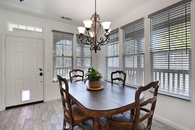 dining room with visible vents, a notable chandelier, baseboards, and wood finished floors