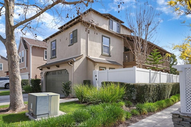 view of front of property featuring an attached garage, fence, and stucco siding