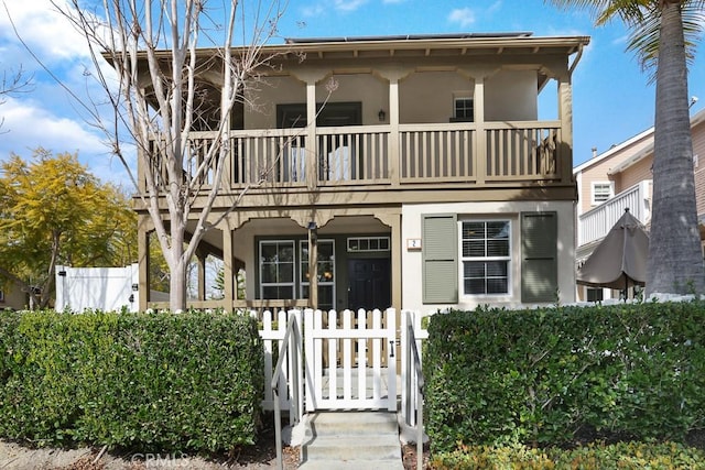 view of front facade featuring a balcony, fence, and stucco siding