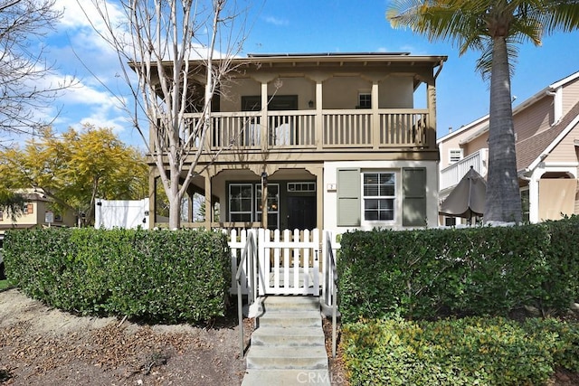 view of front facade with a fenced front yard, a balcony, and stucco siding