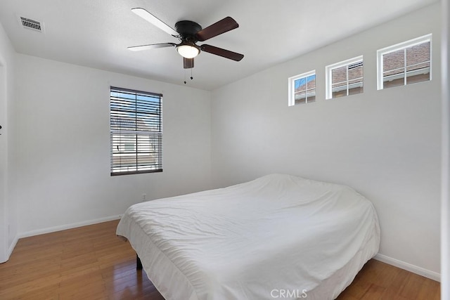 bedroom featuring a ceiling fan, dark wood-style flooring, visible vents, and baseboards