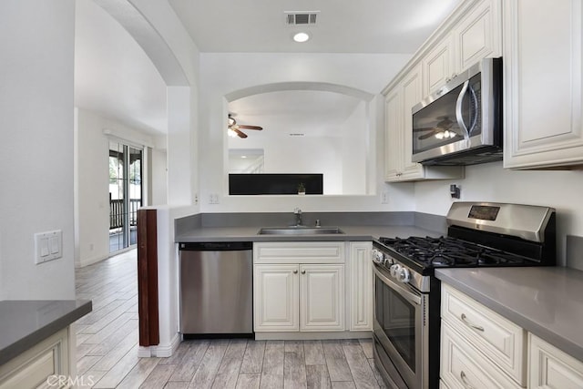 kitchen with stainless steel appliances, dark countertops, visible vents, white cabinets, and a sink