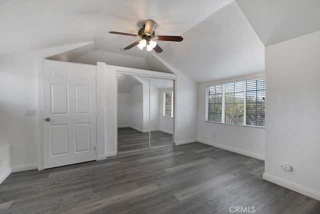 unfurnished bedroom with baseboards, a ceiling fan, lofted ceiling, dark wood-type flooring, and a closet