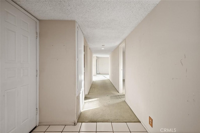 hall featuring light tile patterned floors and a textured ceiling