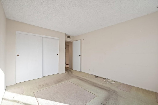 unfurnished bedroom with a closet, light carpet, and a textured ceiling