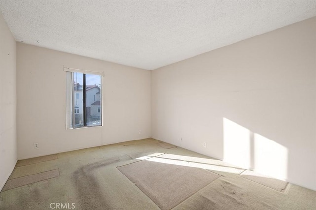 carpeted empty room with a textured ceiling