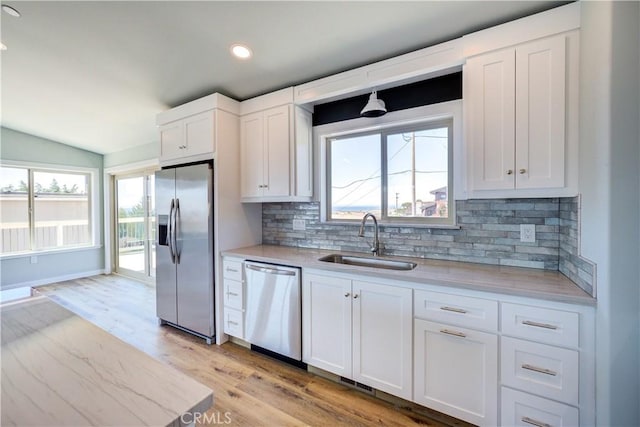 kitchen featuring sink, appliances with stainless steel finishes, tasteful backsplash, white cabinets, and light wood-type flooring