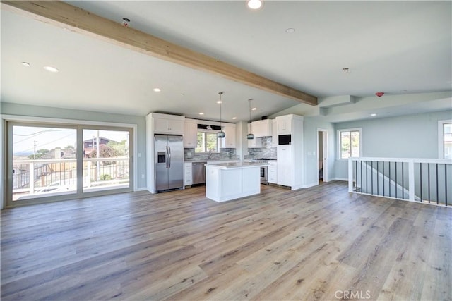 kitchen with lofted ceiling with beams, hanging light fixtures, appliances with stainless steel finishes, a kitchen island, and white cabinets