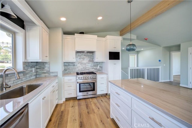 kitchen featuring sink, hanging light fixtures, stainless steel appliances, lofted ceiling with beams, and white cabinets