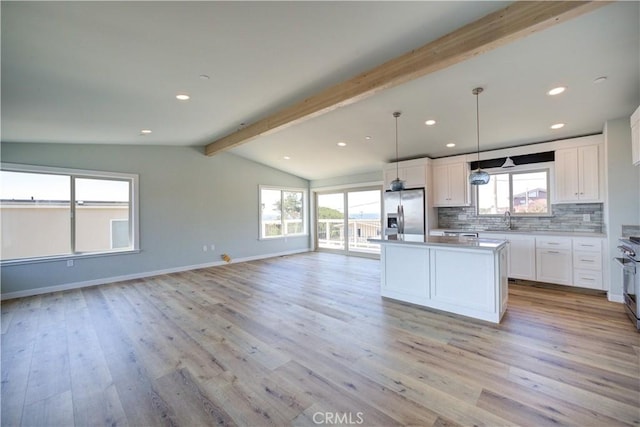 kitchen featuring appliances with stainless steel finishes, white cabinetry, hanging light fixtures, backsplash, and a kitchen island