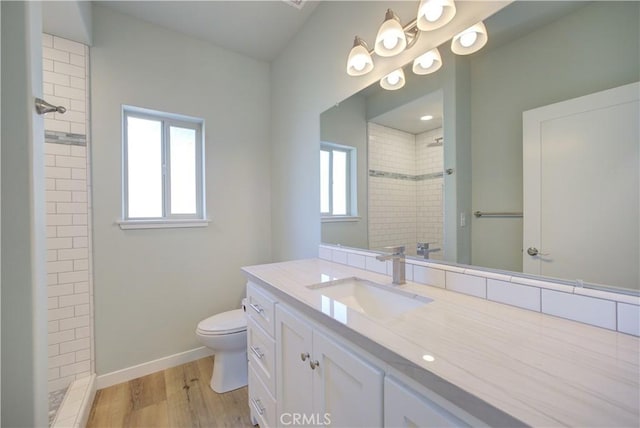 bathroom featuring a tile shower, vanity, hardwood / wood-style flooring, and toilet