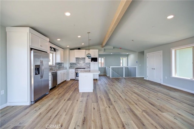 kitchen with appliances with stainless steel finishes, a center island, pendant lighting, and white cabinets