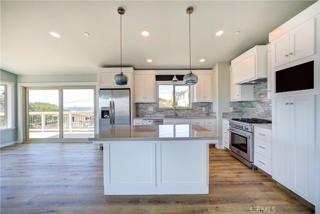 kitchen with sink, appliances with stainless steel finishes, white cabinetry, a center island, and decorative light fixtures