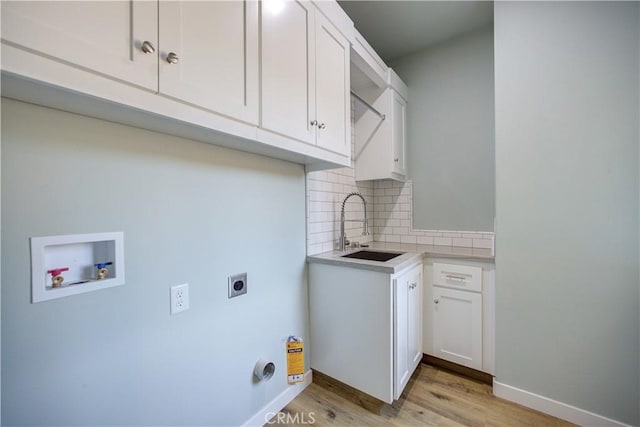 washroom with sink, cabinets, washer hookup, hookup for an electric dryer, and light hardwood / wood-style floors