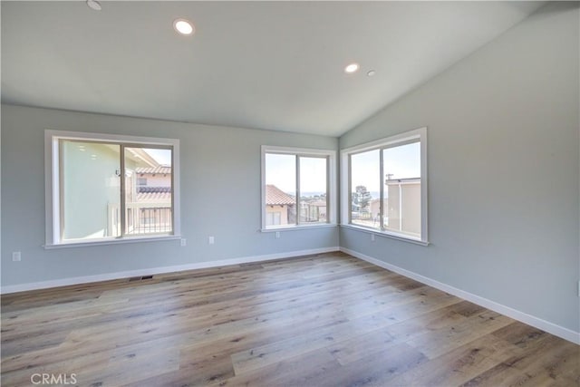 empty room featuring lofted ceiling and light hardwood / wood-style flooring
