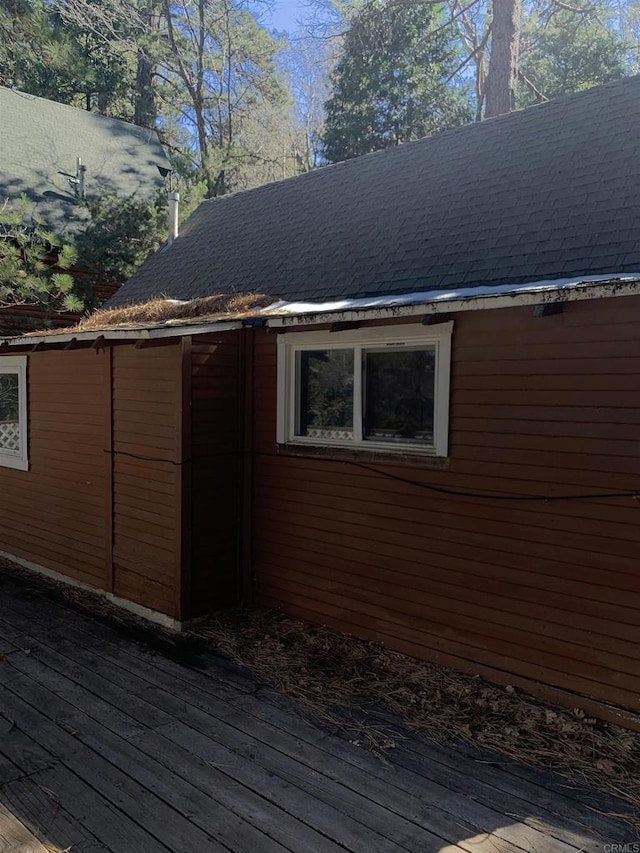 view of side of property featuring roof with shingles and a wooden deck