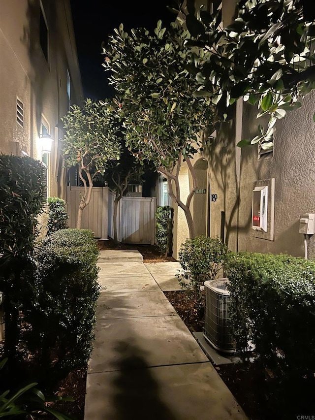 view of side of home with central AC, fence, a patio, and stucco siding