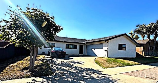 ranch-style house with a garage, concrete driveway, and stucco siding