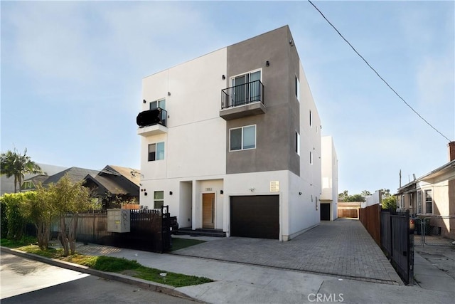 view of front of property featuring fence, an attached garage, and stucco siding