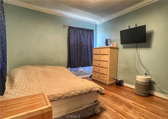 bedroom with ornamental molding, baseboards, and wood finished floors