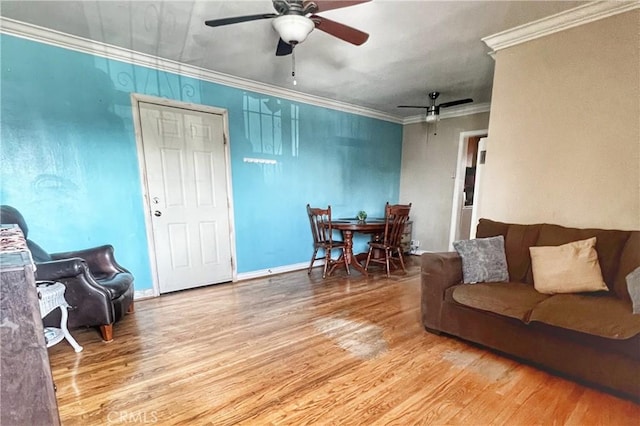 living area featuring ceiling fan, ornamental molding, wood finished floors, and baseboards