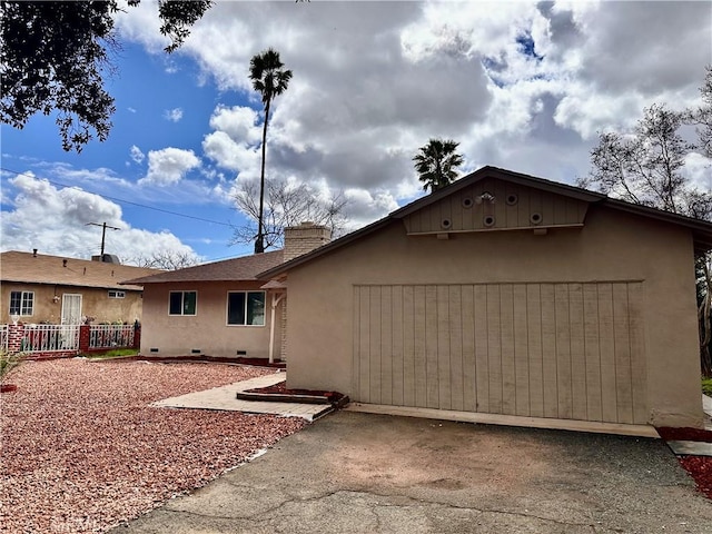 view of front of property featuring stucco siding, driveway, fence, an attached garage, and a chimney