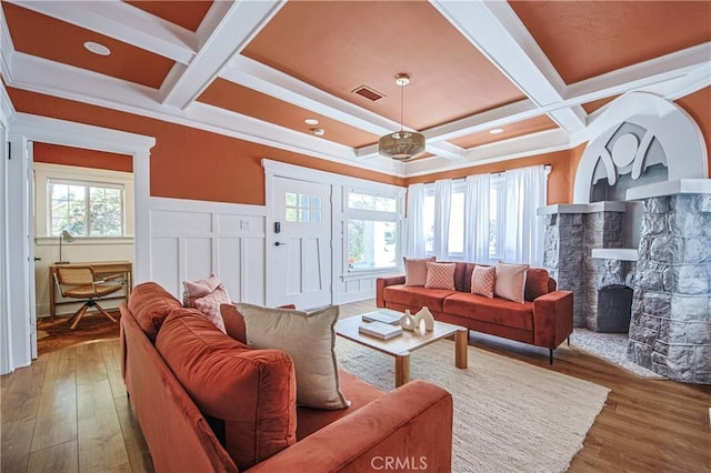 living room with coffered ceiling, hardwood / wood-style floors, and a stone fireplace