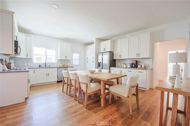 kitchen featuring white cabinetry, appliances with stainless steel finishes, light wood-type flooring, and decorative backsplash