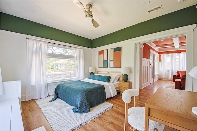 bedroom with multiple windows, coffered ceiling, light hardwood / wood-style floors, and beam ceiling