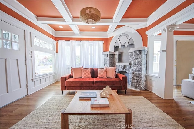 living room featuring ornate columns, a stone fireplace, beamed ceiling, hardwood / wood-style flooring, and coffered ceiling