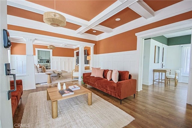 living room featuring ornate columns, wood-type flooring, and beamed ceiling