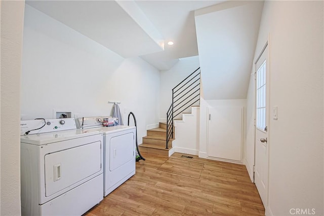 clothes washing area featuring washer and clothes dryer and light hardwood / wood-style flooring