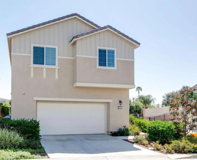 view of front of property with a garage, driveway, a tiled roof, fence, and stucco siding