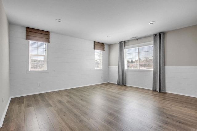 unfurnished room with concrete block wall, visible vents, and wood finished floors