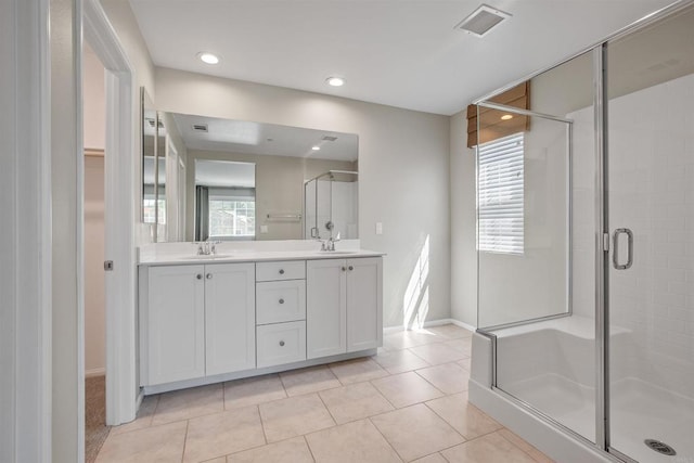 bathroom featuring double vanity, visible vents, a sink, a shower stall, and tile patterned flooring