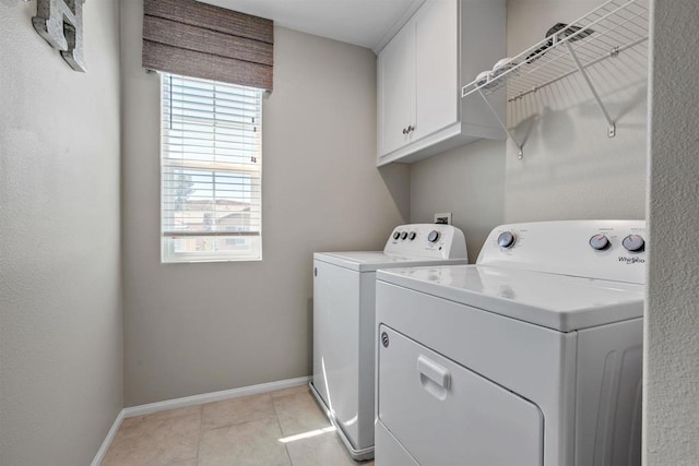 clothes washing area featuring separate washer and dryer, cabinet space, a wealth of natural light, and baseboards