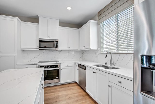 kitchen featuring appliances with stainless steel finishes, white cabinets, and light stone counters