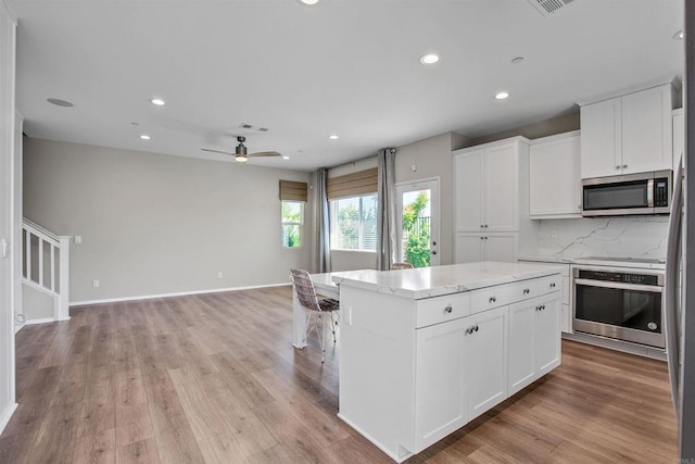 kitchen with open floor plan, appliances with stainless steel finishes, white cabinetry, and a center island