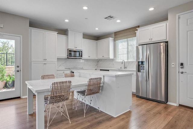 kitchen with stainless steel appliances, a kitchen island, visible vents, and white cabinetry