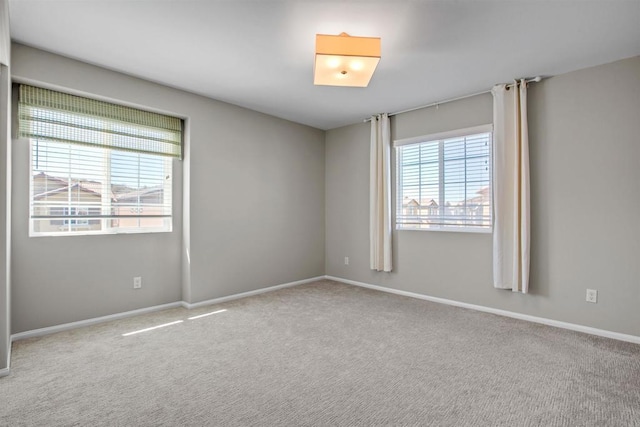 unfurnished room featuring baseboards and light colored carpet