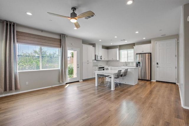 kitchen with appliances with stainless steel finishes, a kitchen island, white cabinetry, and a kitchen breakfast bar