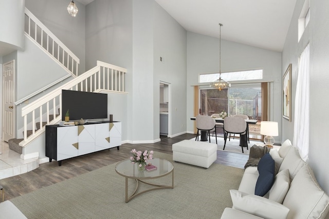 living area with visible vents, wood finished floors, high vaulted ceiling, stairway, and a chandelier