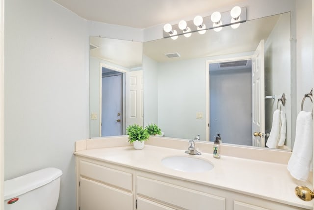 bathroom featuring visible vents, toilet, and vanity
