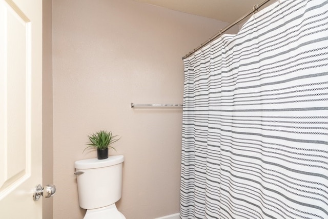 bathroom with a shower with curtain and toilet