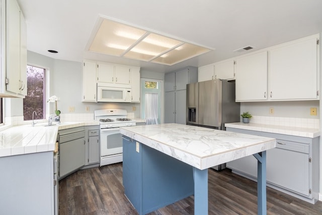 kitchen with visible vents, dark wood finished floors, a wealth of natural light, and white appliances