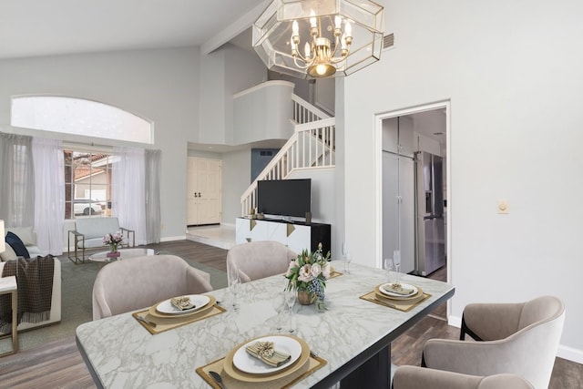 dining area with high vaulted ceiling, a chandelier, stairs, wood finished floors, and beamed ceiling