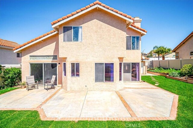 rear view of property featuring fence, stucco siding, a patio area, and a tiled roof
