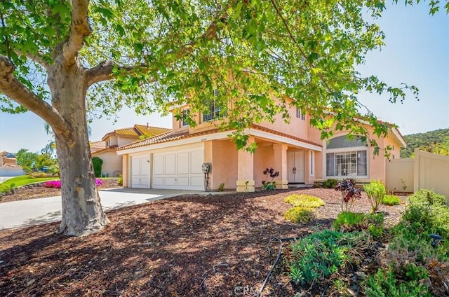 view of front of home featuring concrete driveway, fence, a tile roof, and stucco siding