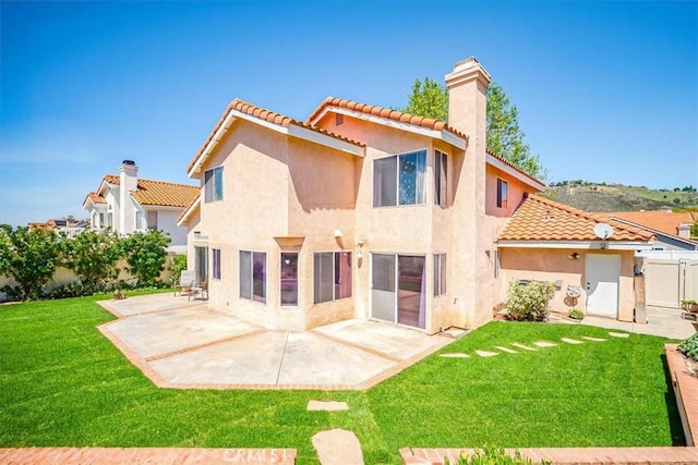 rear view of house featuring fence, a chimney, a tile roof, and stucco siding